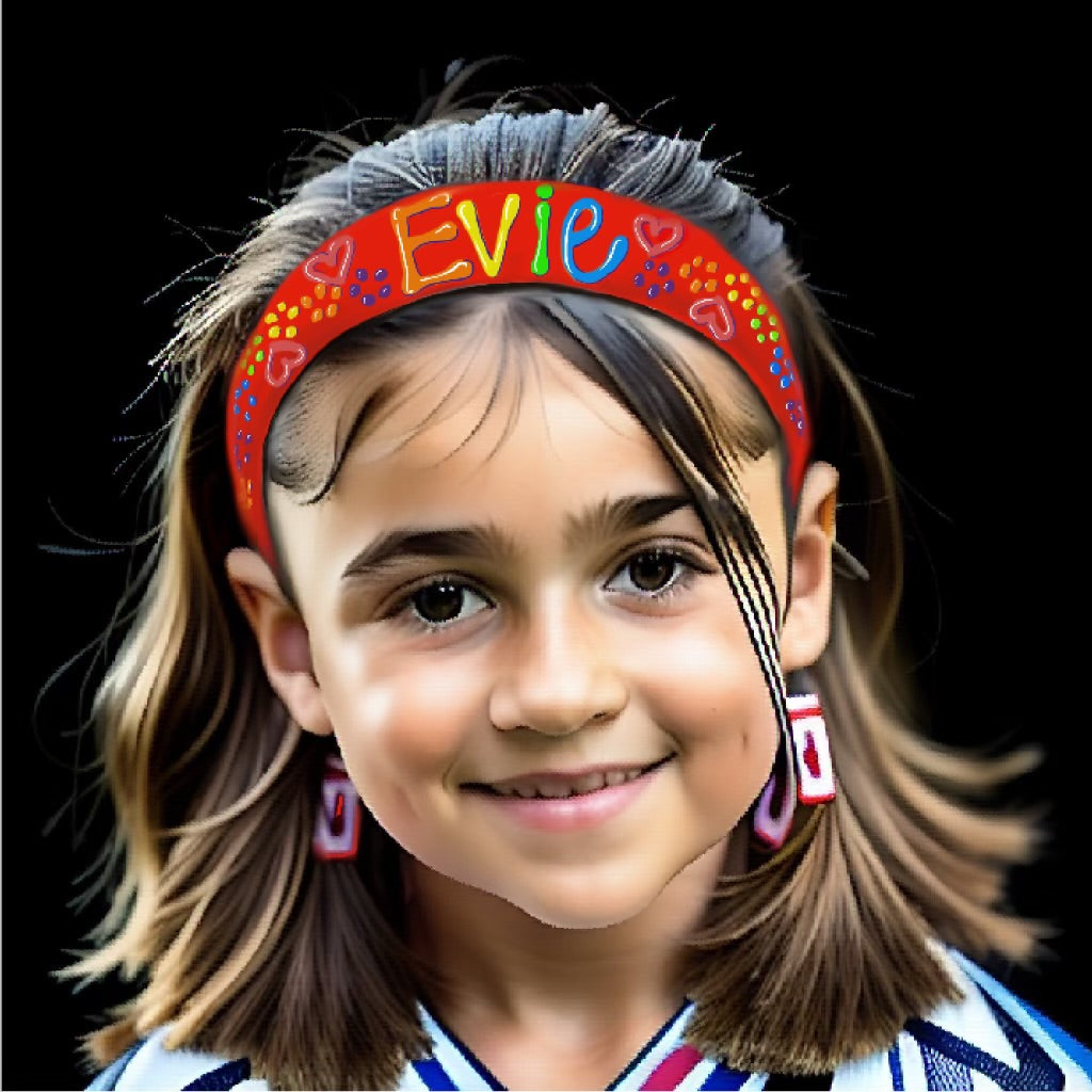 Girlwith brown hair and dark eyes smiling. she's wearing earrings and a red hairband with the name Evie.